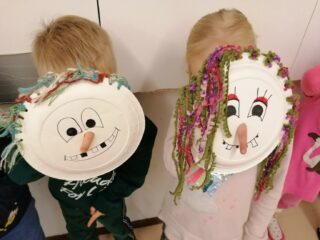 Kaksi muskarilaista pitävät kasvojensa edessä itse paperilautasista tekemiään maskeja