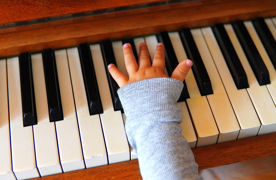 Pianon koskettimet ja soittajan käsi.