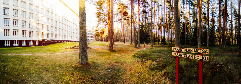 Paimion parantolan potilassiipi vasemmalla ja oikealla Parantolan metsään lähtevän Parantolan polun kyltti