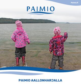 Kaksi tyttöä sadeasuissa katsoo merelle. Kuvassa myös Paimion logo.