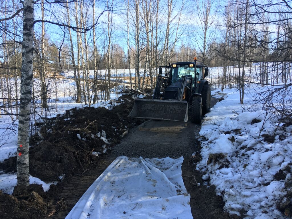 Suodatinkankaan päälle ajettiin traktorin etukuormaajalla paksu kerros mursketta.