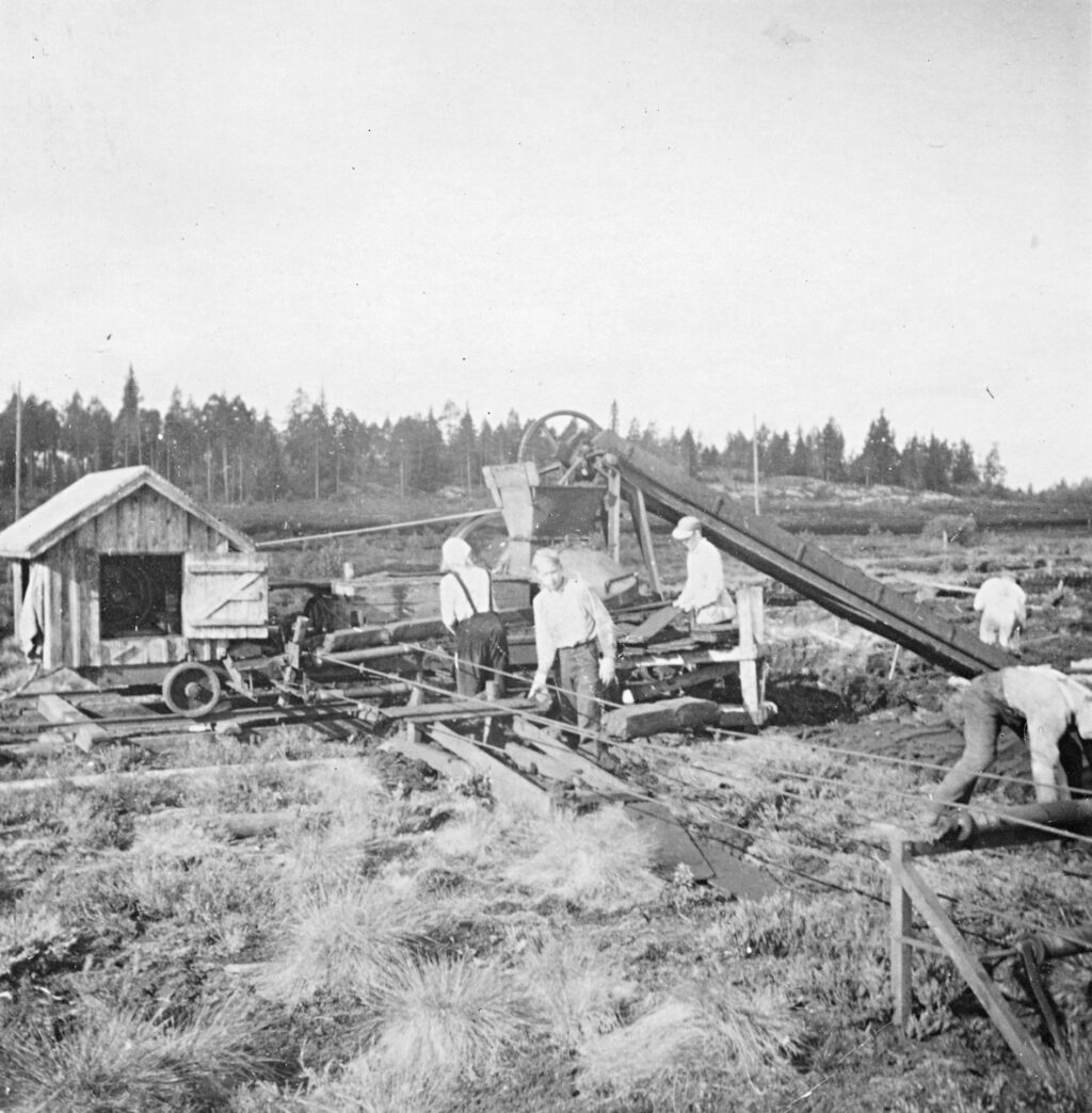 Mustavalkoinen valokuva, jossaihmisiä on työskentelemässä pehkutehtaalla.