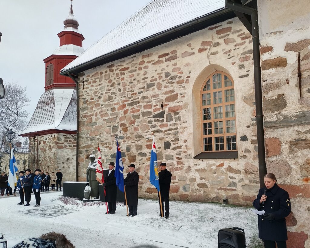 Kunniavartio lippuineen Paimion kirkon viereisellä sankarihaudalla. Oikealla näkyy puhujana tilaisuudessa toiminut upseerioppilas Jutta Salmela.