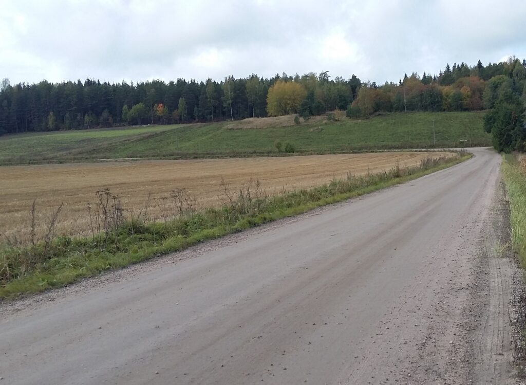 Hiekkatie syksyisen peltoalueen keskellä.
