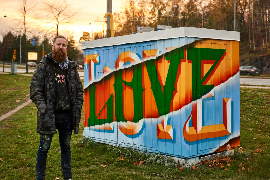 Mies seisoo graffiteilla maalatun kontin edessä.