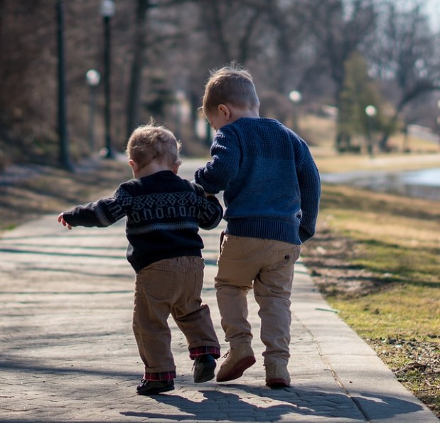 Kaksi lasta selin kuvattuna kävelemässä.