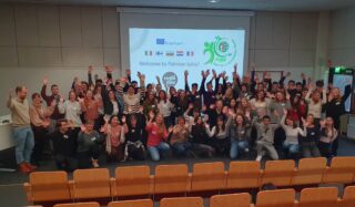 Ryhmäkuva kokoustilasta, jonka valkokankaalla lukee Welcome to Paimion lukio. Kuvassa näkyy myös eri maiden lippuja ja Erasmus-logo.