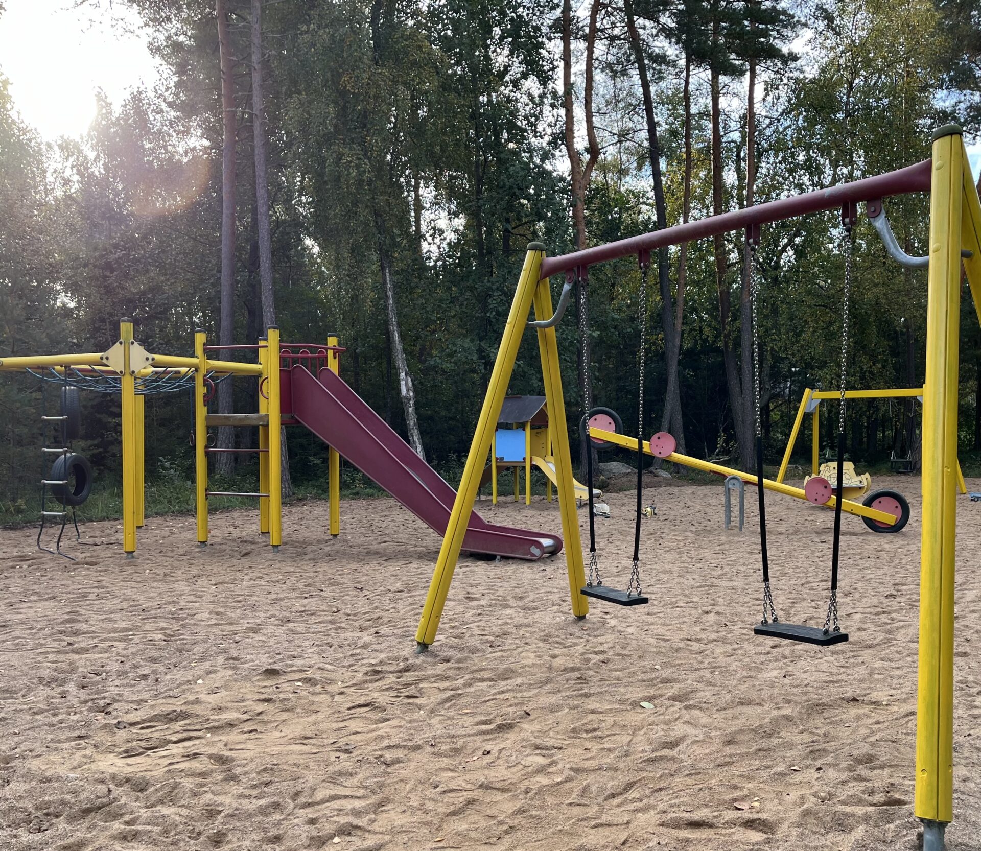 Leikkipuistossa erilaisia kiipeilytelineitä, etualalla hiekkaa.