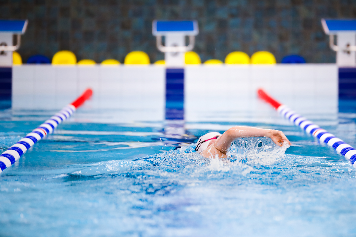 Yksinäinen uimari ui rataköysien sisäpuolella uimahallissa.