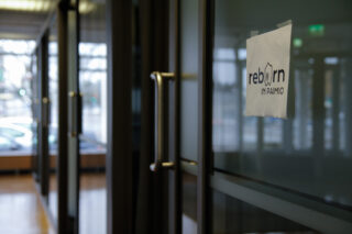 Lasiset työhuoneet sivusta kuvattuna. Etualalla lappu, jossa "ReborninPaimio"-logo.