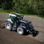 Hytillinen traktori äestämässä peltoa aurinkoisessa säässä.