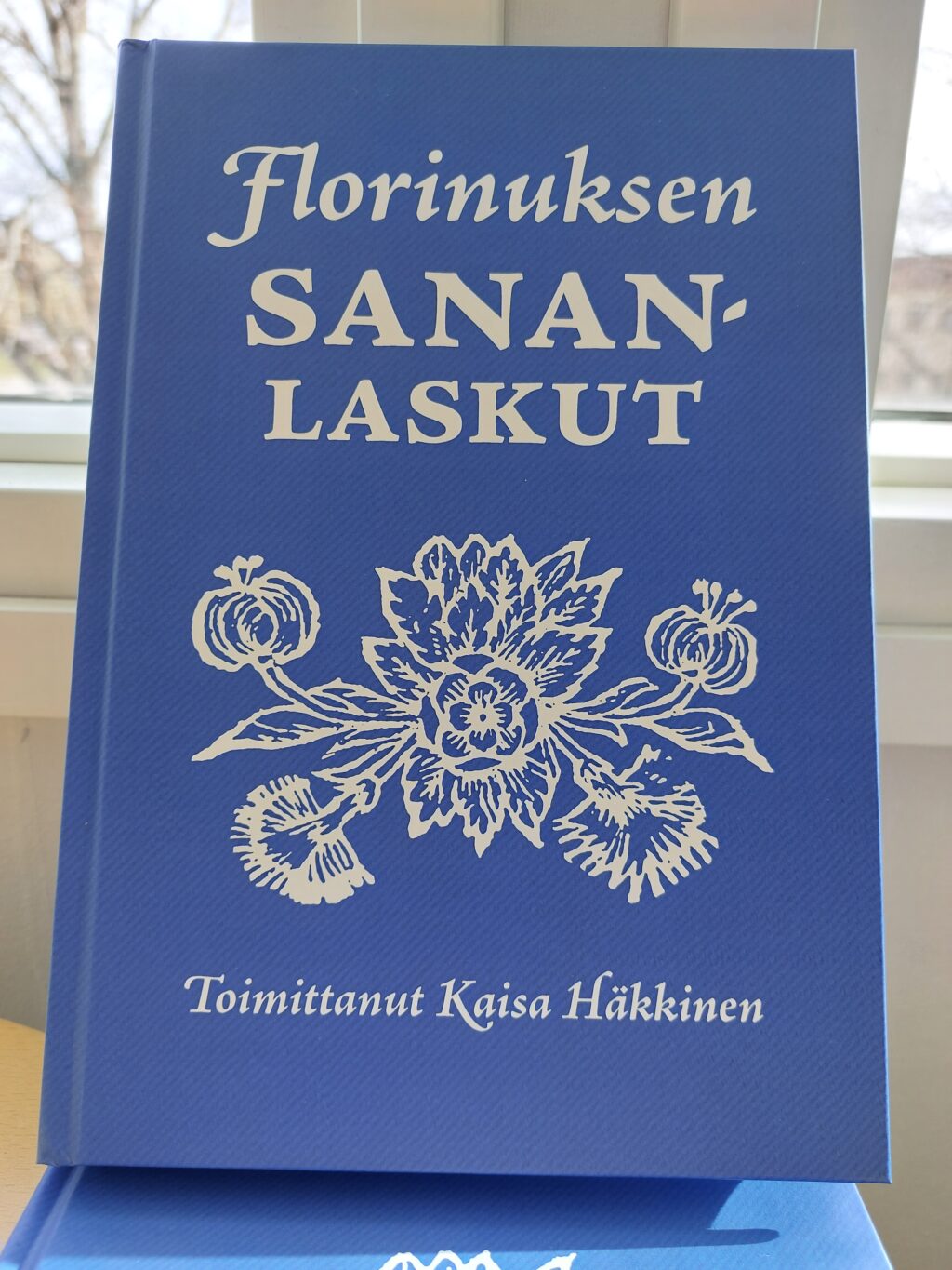 Sinikantinen kirja, jossa teksti Florinuksen sananlaskut, toimittanut Kaisa Häkkinen sekä kukkakuvio.