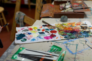 Maalaustarvikkeita ja värikkäitä maaleja pöydällä