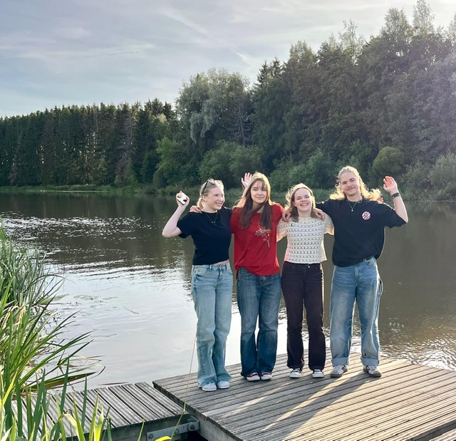 Neljä nuorta seisoo laiturilla, joen äärellä.