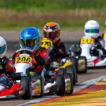 Kuusi karting-autoa ajamassa radalla peräkkäin.