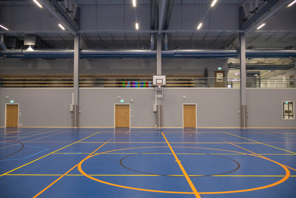Liikuntasali kuvattuna keskeltä. Toisessa kerroksessa näkyy taustalla katsomo.