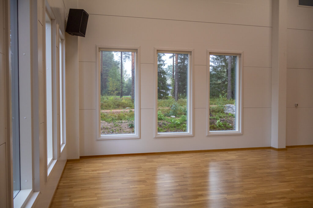 Sisäliikuntahallin monitoimisalit. Ikkunoista näkyy metsäinen maisema.