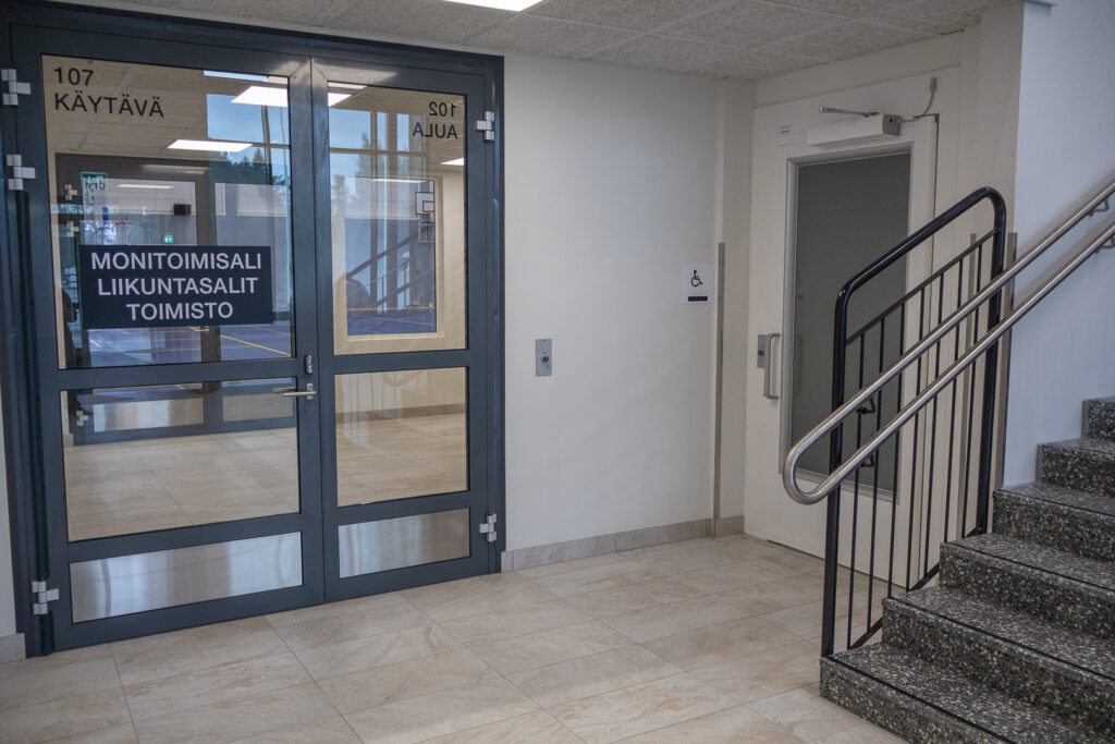 Rappusten takana oleva invahissi. Vasemmalla ovi monitoimisaliin ja oikealta lähtee portaat yläkertaan, katsomoon.