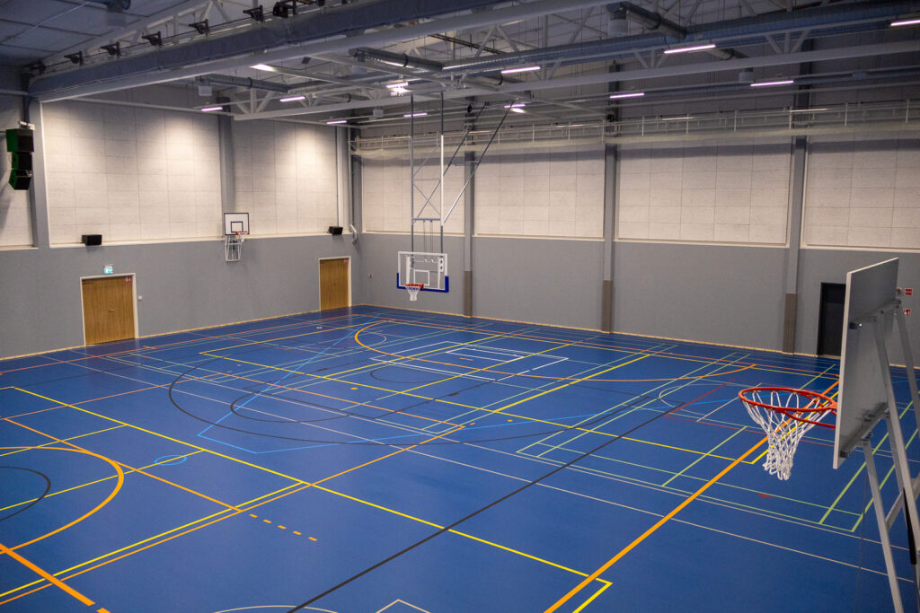 Sisäliikuntahallin liikuntasalia kuvattu toisen kerroksen katsomosta oikeaan suuntaan. Kuvassa näkyvissä myös koripallokoreja.