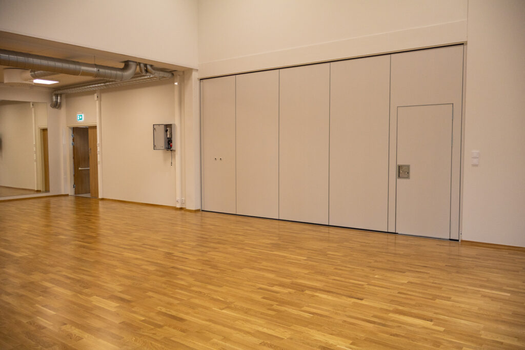 Sisäliikuntahallin monitoimisalit. Taustalla avattava seinän kohta.