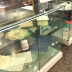 Pitsinnypläystöitä esillä kirjaston vitriinissä.