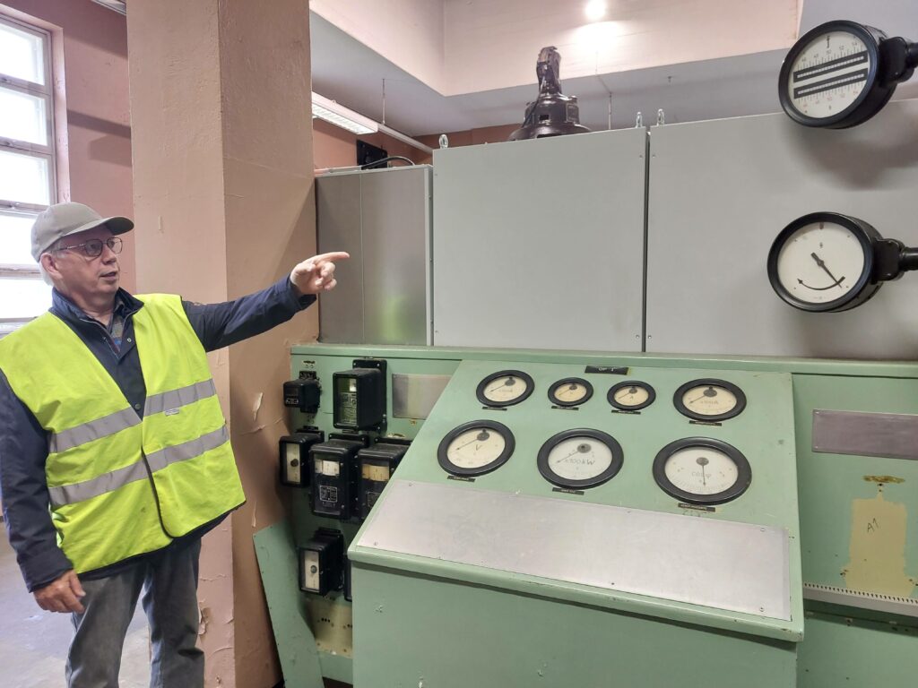 Mies keltainen huomioliivi päällää esittelee voimalaitoksessa laitteistoja.
