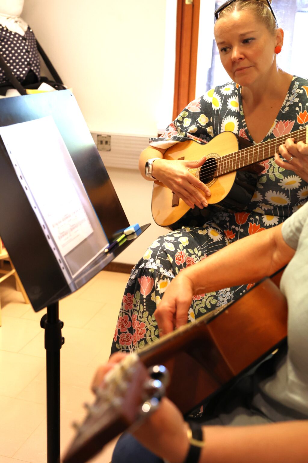 Nainen opettaa oppilaalle kitaransoittoa