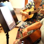 Nainen opettaa oppilaalle kitaransoittoa