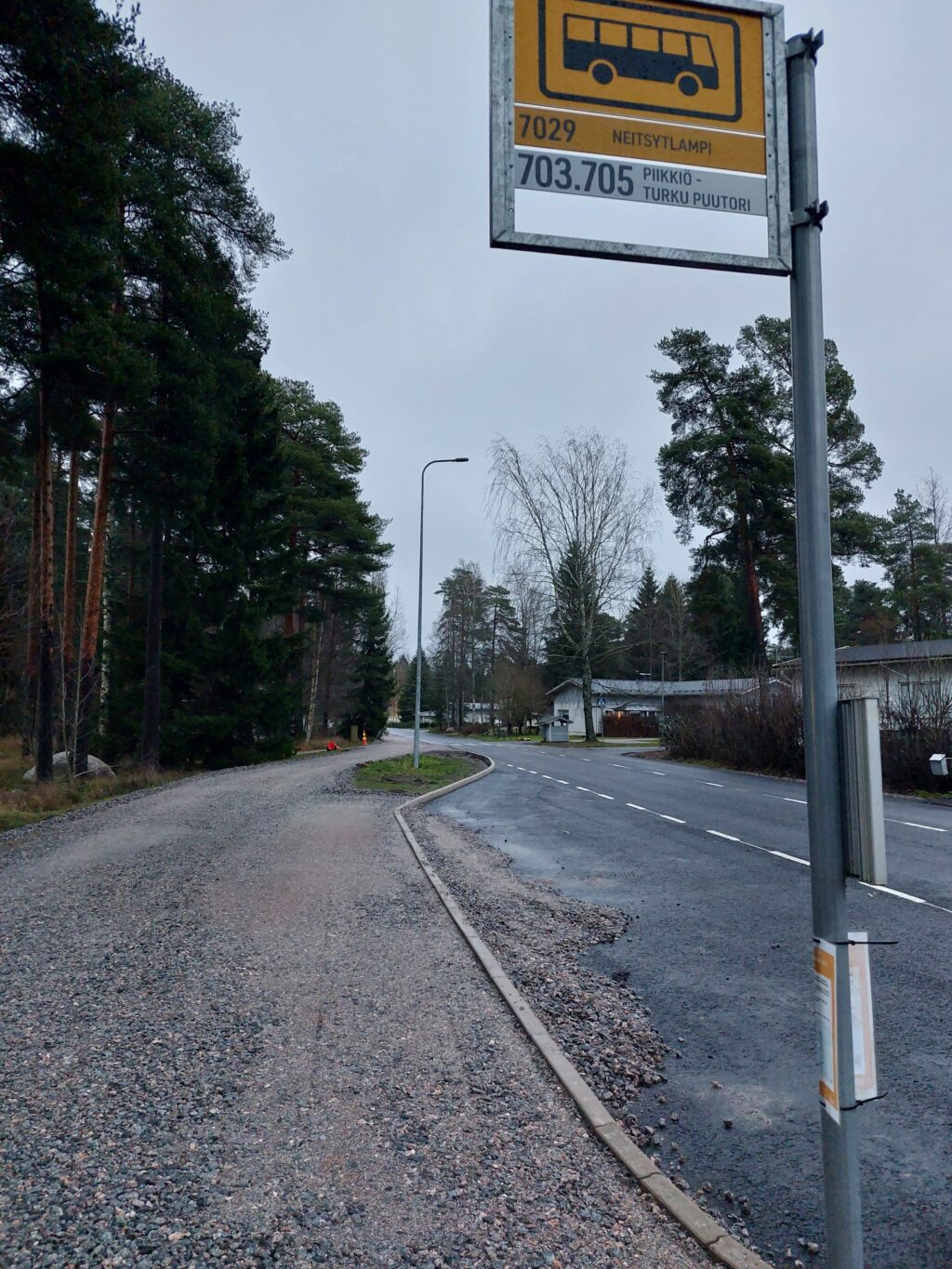 Etuaalalla busspysäkki, jonka kahdessa laatassa tekstit: 7029 Neitsytlampi sekä 703, 705 Piikkiö - Turku, Puutori.