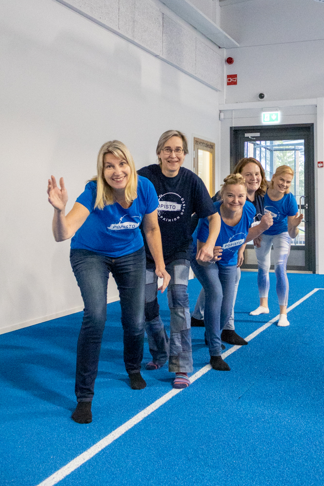 Viisi naista Paimion sisäliikuntahallin juoksuradalla päällään siniset t-paidat