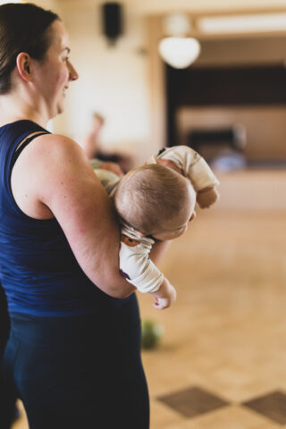 Nainen pitää käsivarsillaan vauvaa vauvajumpassa 