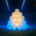 Pimeän taustan edustalla isokokoisista lumipalloista rakennettu jättilumilyhty.