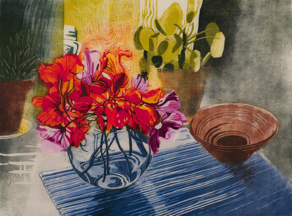 Taideteoksessa punaisia kukkia maljakossa sinisen pöytäliinan päällä.