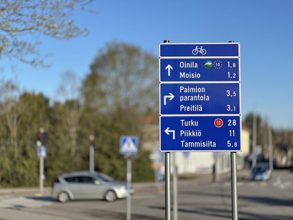Pyöräilyreittien opaste. Opastetaulussa kerrotaan suunnat ja etäisyydet eri kohteisiin ja lisäksi ilmaistaan pyörämatkailureittien suunnat.