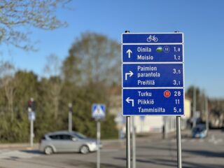 Pyöräilyreittien opaste. Opastetaulussa kerrotaan suunnat ja etäisyydet eri kohteisiin ja lisäksi ilmaistaan pyörämatkailureittien suunnat.