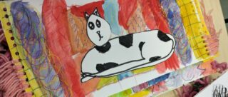 Värikäs piirrokuva, jonka pääosassa mustavalkoinen kissa.