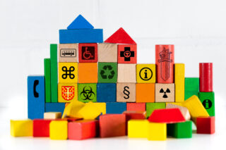 Erilaisia ja erivärisiä puupalikoita. Osa on pinottu rakennelmaksi. Joissakin palikoissa on maalattu symboleja tai kuvia..