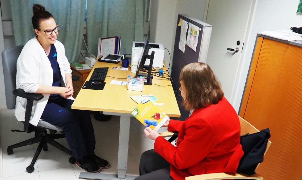 Sairaanhoitaja ja asiakas keskustelevat vastaanottohuoneessa.