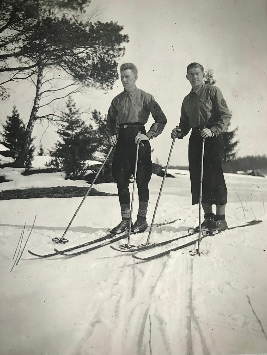 1930-luvulla otetussa mustavalkoisessa kuvassa kaksi miestä hiihtovarusteissa lumisessa maiosemassa.