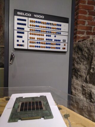 Taustalla suuri vanha tietokone ja etualalla iso vanha muistikortti.