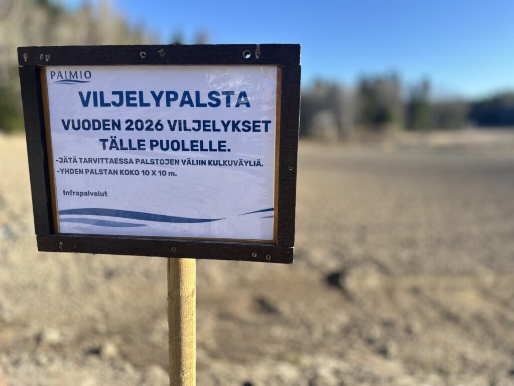 Peltoalueen reunalla oleva kyltti, jossa Paimion kaupungin logoo ja teksti Viljelypalsta. Vuoden 2026 viljelykset tällä puolella.