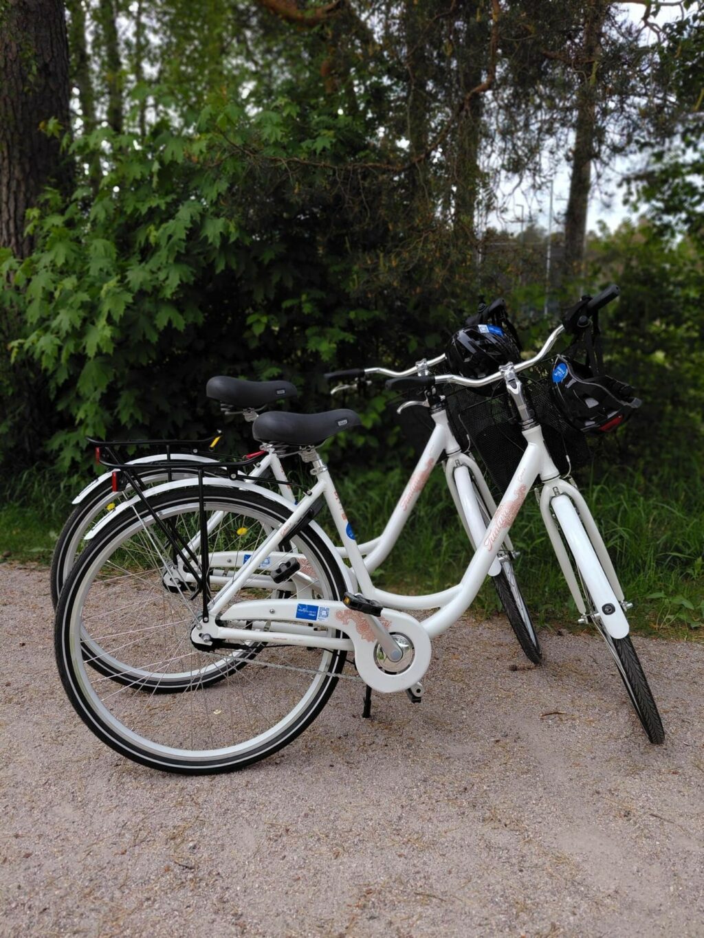 Kaksi valkoista polkupyörää ulkona hiekka-alustan päällä.