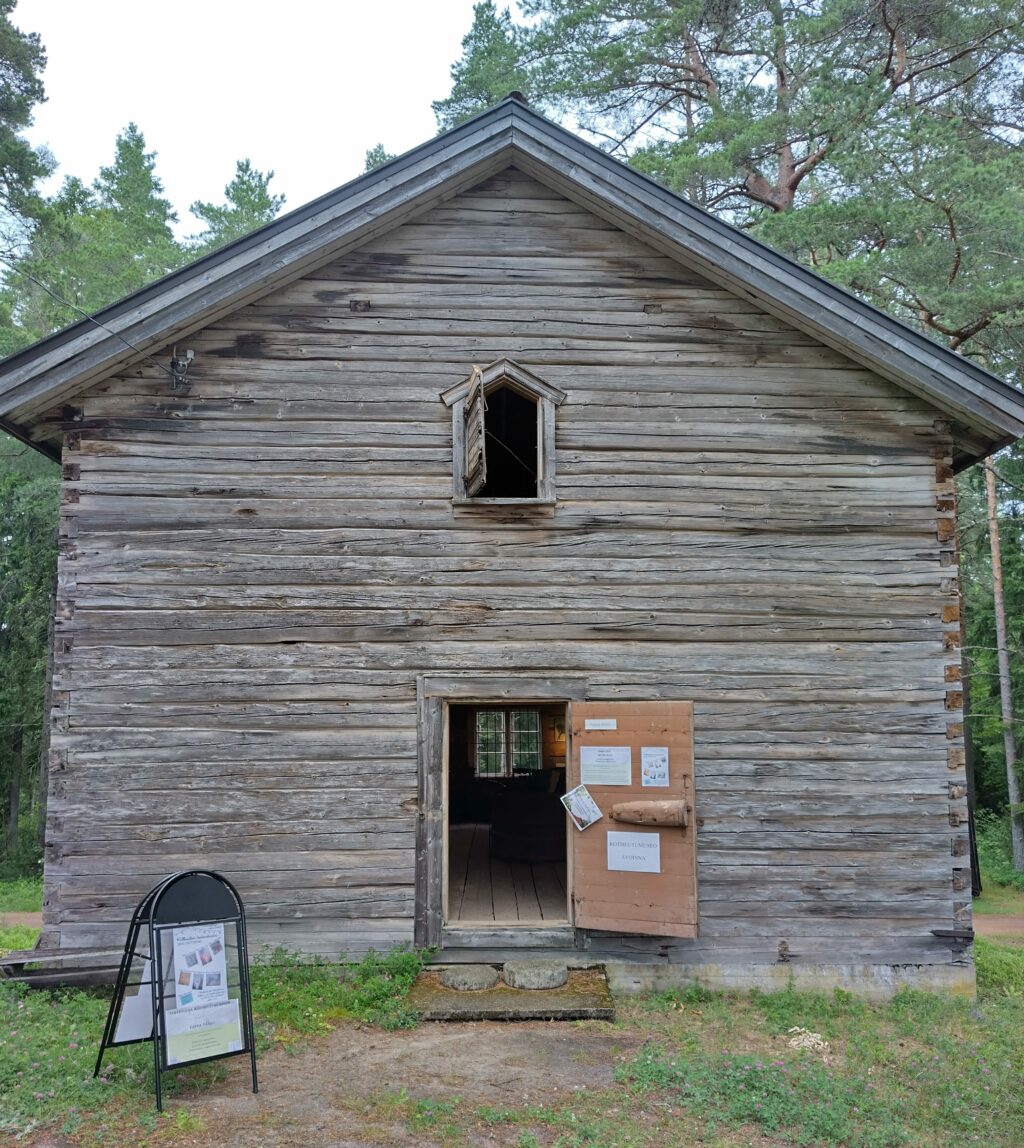 Iso puinen viljamakasiini, jossa avoin ovi sekä toisessa kerroksessa avoin ikkuna