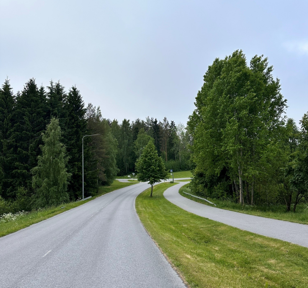 Asvalttitie sekä kevyenliikenteenväylä kulkevat vierekkäin samansuuntaisina kohti metsäistä aluetta.