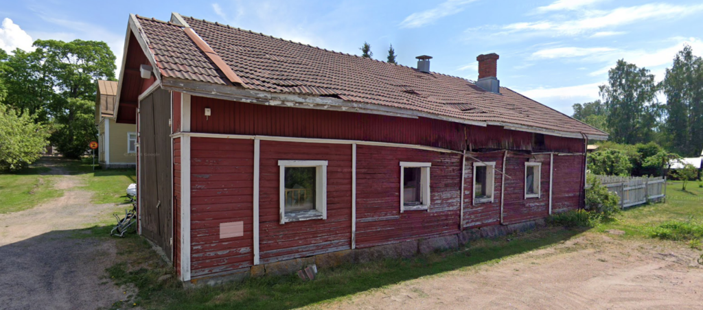 Huonokuntoinen, punainen puurakenteinen kirjastoautotalli.