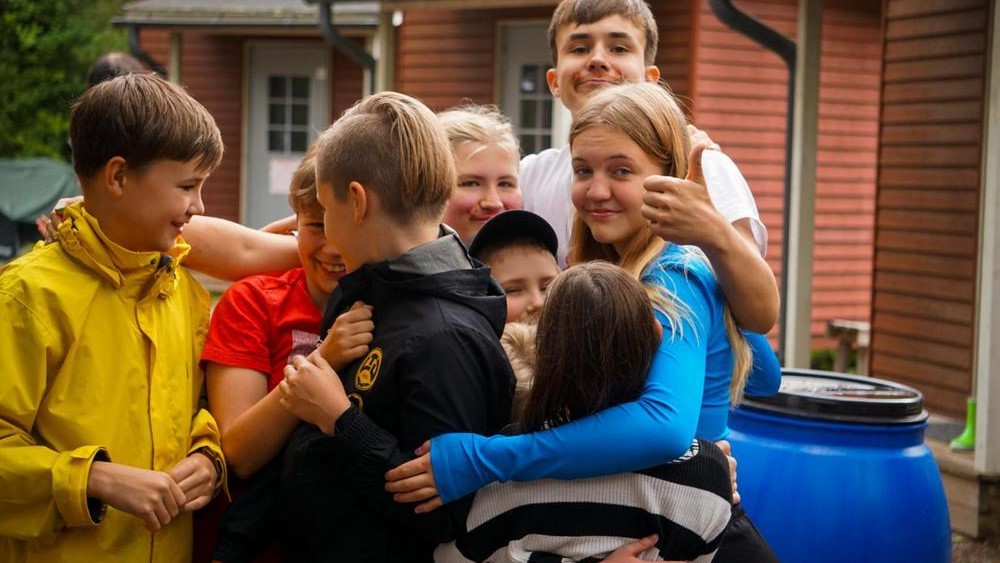 Ryhmäkuvassa noin teini-ikäisiä lapsia ulkona kesällä.